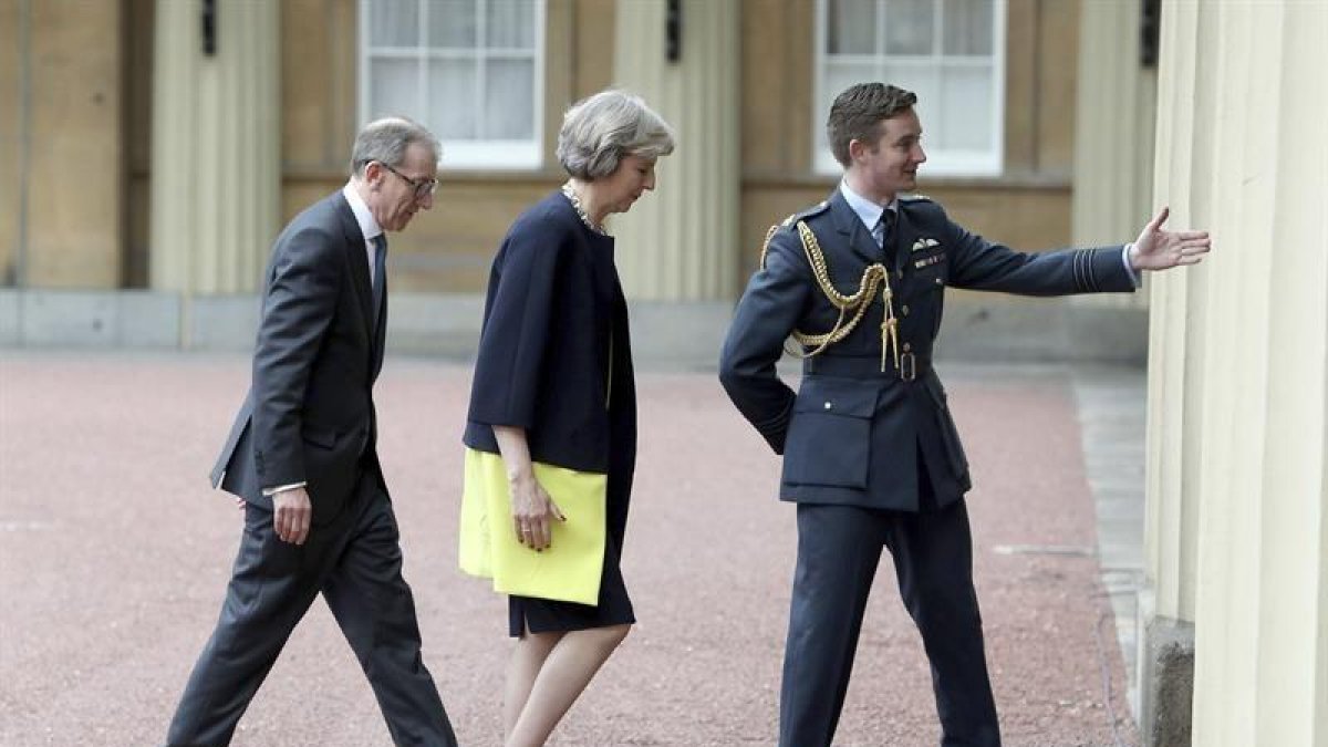 La conservadora, Theresa May (c), y su marido, Philip John (i), a su llegada al palacio de Buckingham para recibir el mandato de la reina Isabel II para formar gobierno.-EFE/Dominic Lipinski