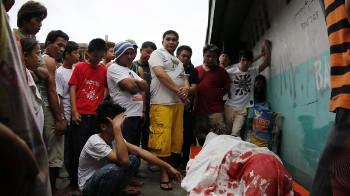 Un grupo de familiares permanece junto al cuerpo de un supuesto drogadicto asesinado durante una operación policial contra las drogas ilegales al interior de una mezquita en Manila.-FRANCIS R. MALASIG / EFE