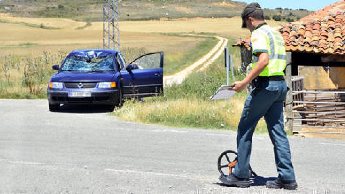 Un agente toma mediciones ante el turismo implicado en el accidente. / ÁLVARO MARTÍNEZ-