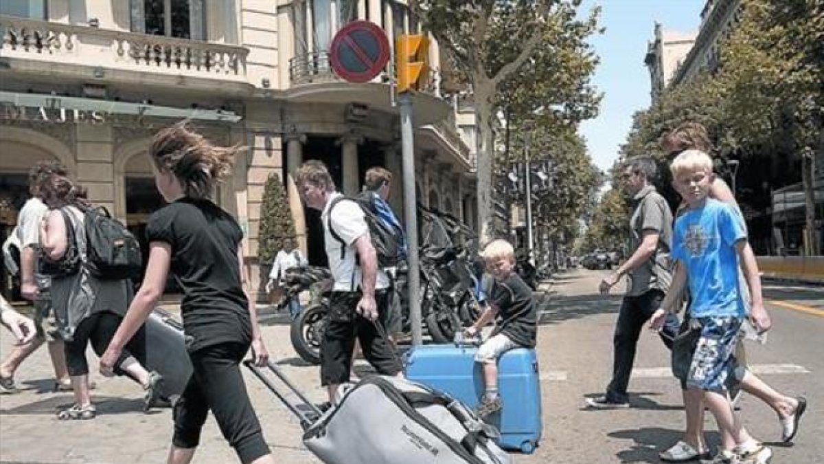 Turistas con maletas rumbo a su alojamiento.-JOAN CORTADELLAS