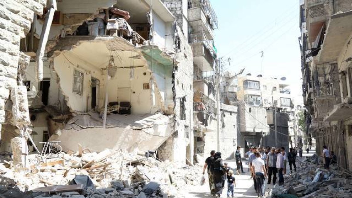 Vecinos de Alepo pasan junto a un edificio destruido en un bombardeo del régimen, este domingo.-Foto:   KHALED KHATEB / AFP / JALED JATEB