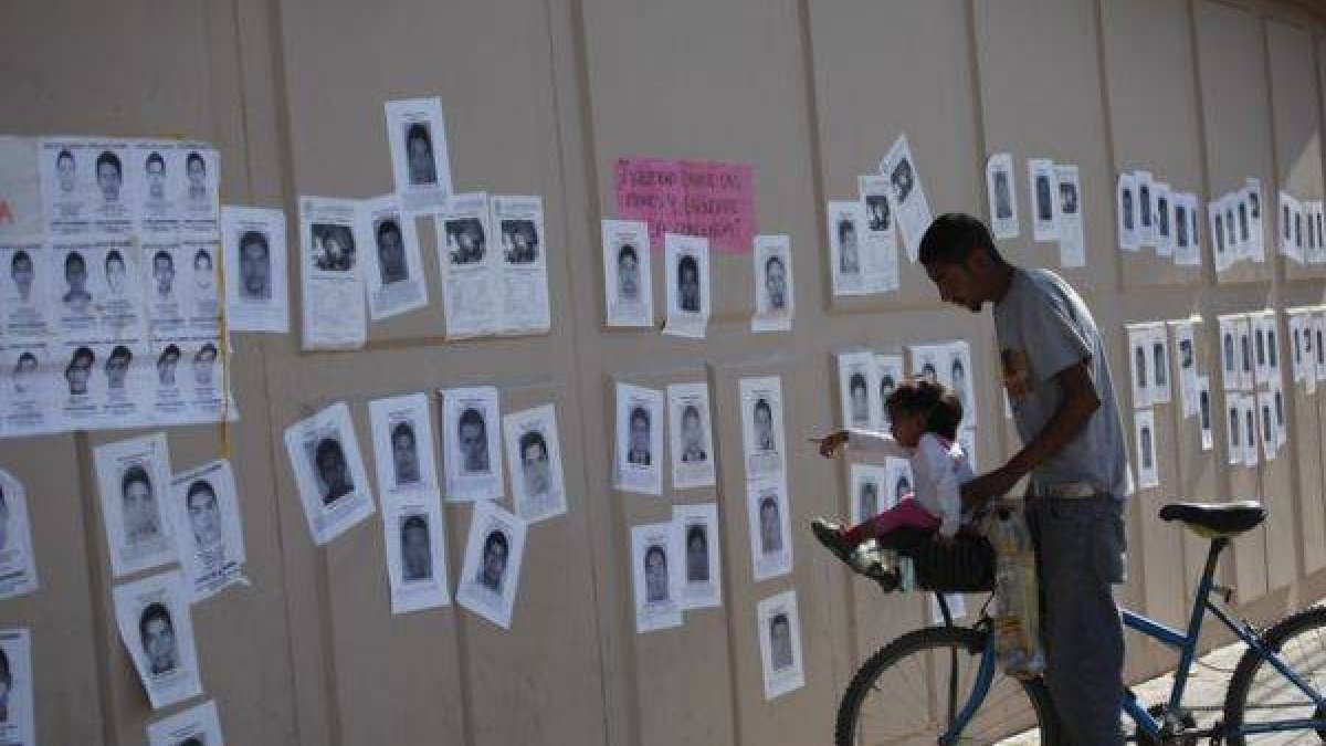 Una niña señala fotografías de los estudiantes desaparecidos, este jueves en un mural en Ciudad Juárez.-Foto: REUTERS / STRINGER