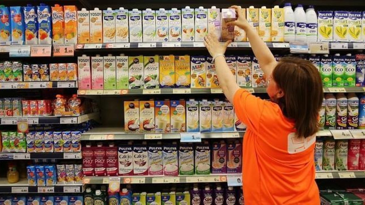 Una trabajadora ordena los productos en la estantería de un supermercado.-RICARD CUGAT