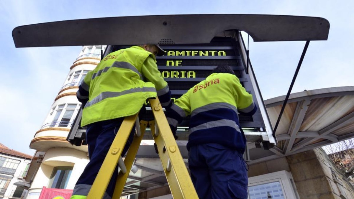 Dos operarios municipales trabajan en un panel informativo.-ÁLVARO MARTÍNEZ