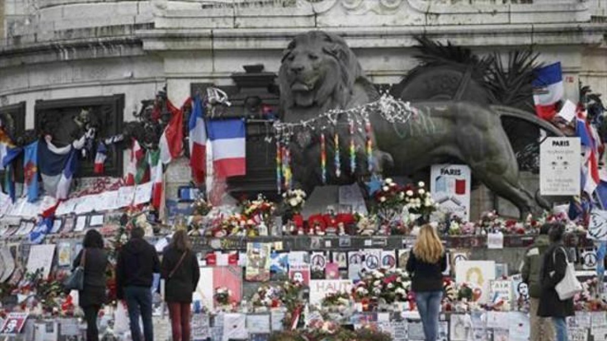 Homenajes a las víctimas en varios puntos de París. Sobre estas líneas, la placa conmemorativa en las antiguas oficinas de 'Charlie Hebdo'. A la derecha, un lector del último número de la revista en Niza.-REUTERS / CHARLES PLATIAU / ERIC GAILLARD / AP / CHRISTOPHE ENA / EFE / BENOIT TESSIER