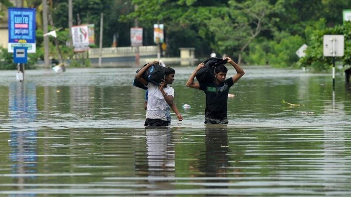Dos jóvenes caminan entre las aguas a unos 17 kilómetros de la capital de Sri Lanka, Colombo.-ISHARA S KODIKARA
