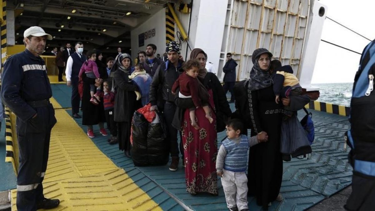 Refugiados y migrantes desembarcan del ferri 'Eleftherios Venizelos' a su llegada al puerto de Elefsina, a 20 kilómetros al noroeste de Atenas, procedentes de Lesbos, este lunes.-EFE / YANNIS KOLESIDIS