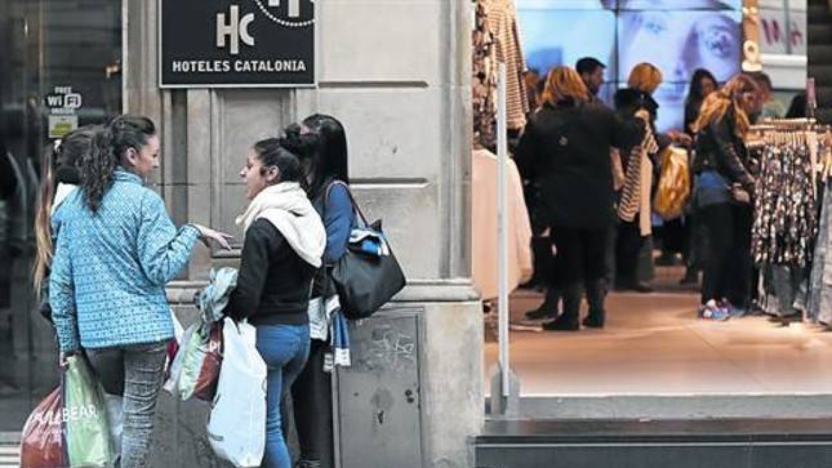 Un grupo de jóvenes charla después de ir de compras en el primer día de rebajas de invierno en Barcelona.-Foto: DANNY CAMINAL
