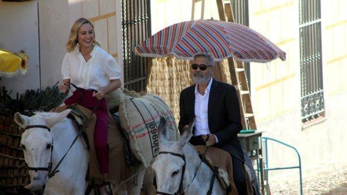 George Clooney y Brie Larson, a lomos de sendos burros, por el centro de Navalcarnero (Madrid).-AYUNTAMIENTO DE NAVALCARNERO