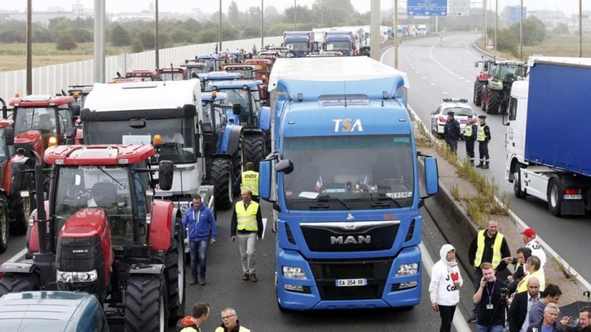 Trabajadores portuarios, camioneros, granjeros y residentes protestan en la autopista, este lunes, en Calais.-REUTERS / CHARLES PLATIAU
