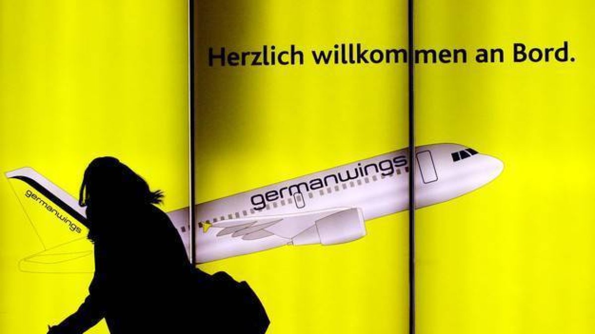 Una mujer pasea por delante de un cartel publicitario de Germanwings en el aeropuerto de Colonia, en Alemania.-Foto: OLIVER STRATMANN / AFP
