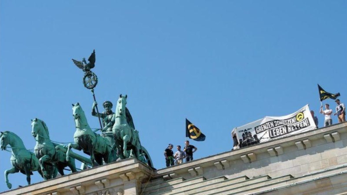 Los ultras de Movimiento Identitario, en lo alto de la Puerta de Brademburgo.-EFE / PAUL ZINKEN