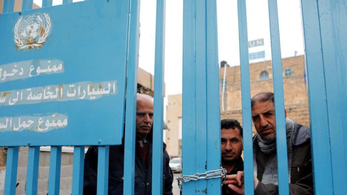 Un grupo de palestinos detrás de la valla de la oficina de la agencia de la ONU para los refugiados palestinos (UNRWA) durante una protesta en la ciudad de Cisjordania.-EFE / ABED AL HASHLAMOUN