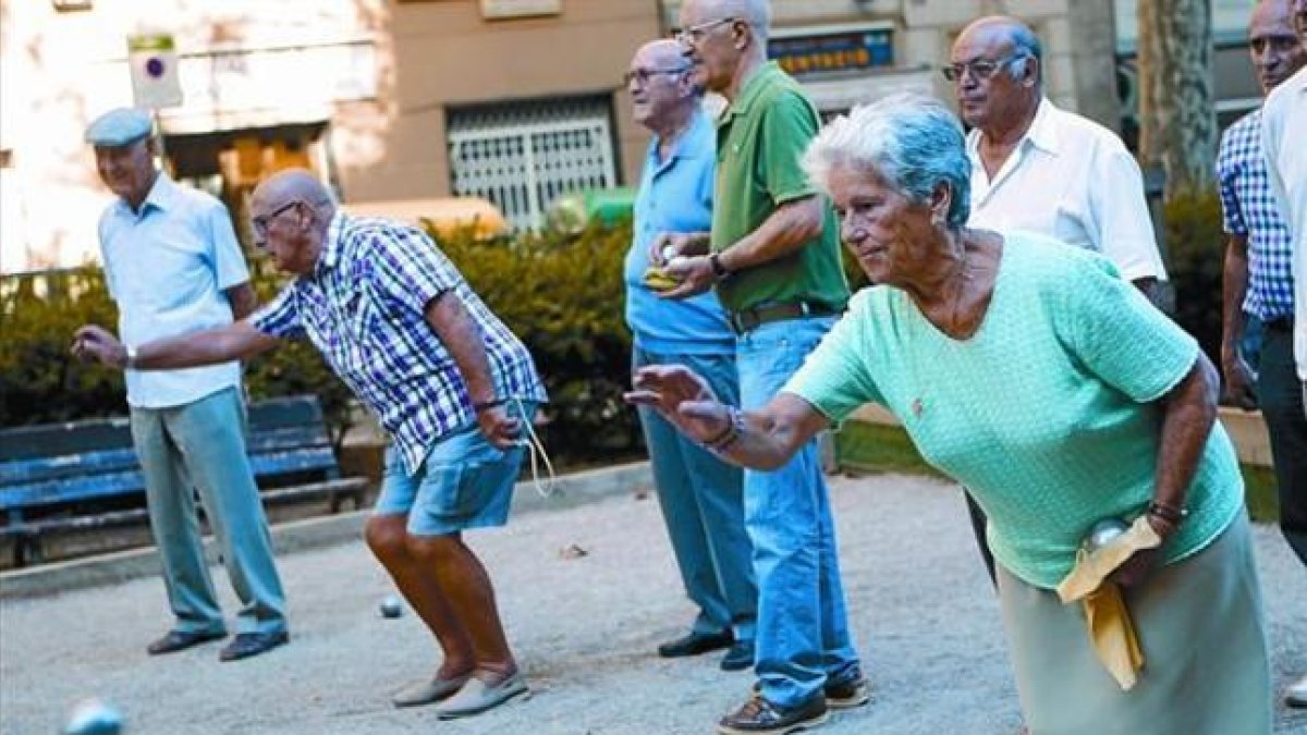 Un grupo de pensionistas juega a petanca en un parque de Barcelona.-ALBERT BERTRAN