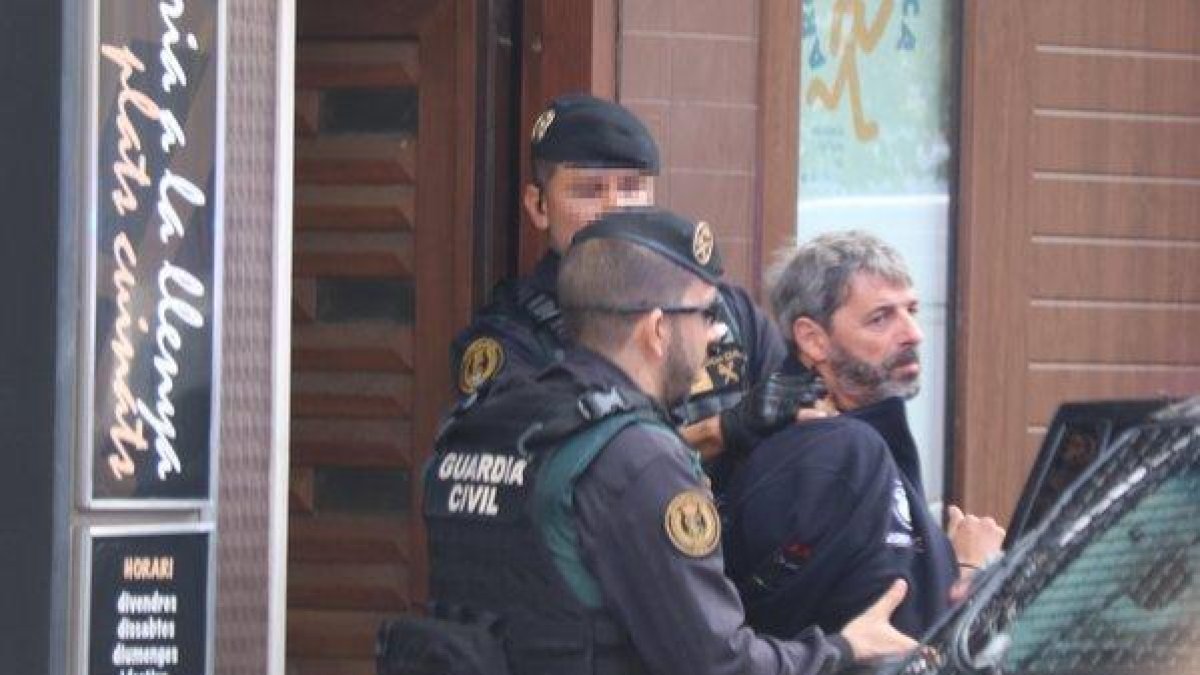 Dos agentes de la Guardia Civil se llevan un detenido en Sabadell en el marco de la operación que ha acabado con nueve miembros de CDR arrestados.-MIQUEL CODOLAR
