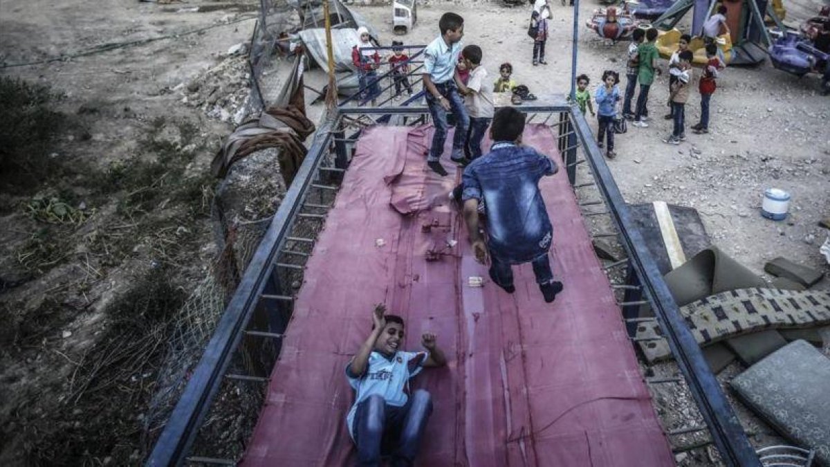 Niños sirios juegan en un trampolín durante el segundo día de la festividad musulmana de Eid Al Adha, en Douma, este martes.-EFE / MOHAMMED BADRA