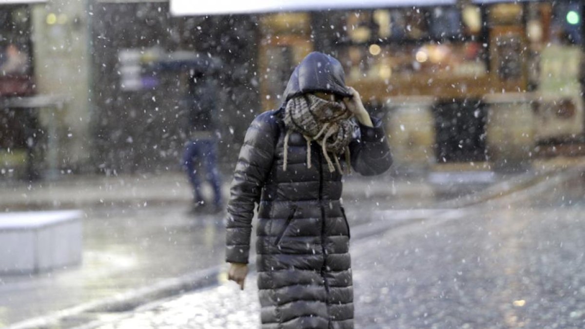 Una persona se protege de la nieve en la jornada de ayer.-LUIS ÁNGEL TEJEDOR