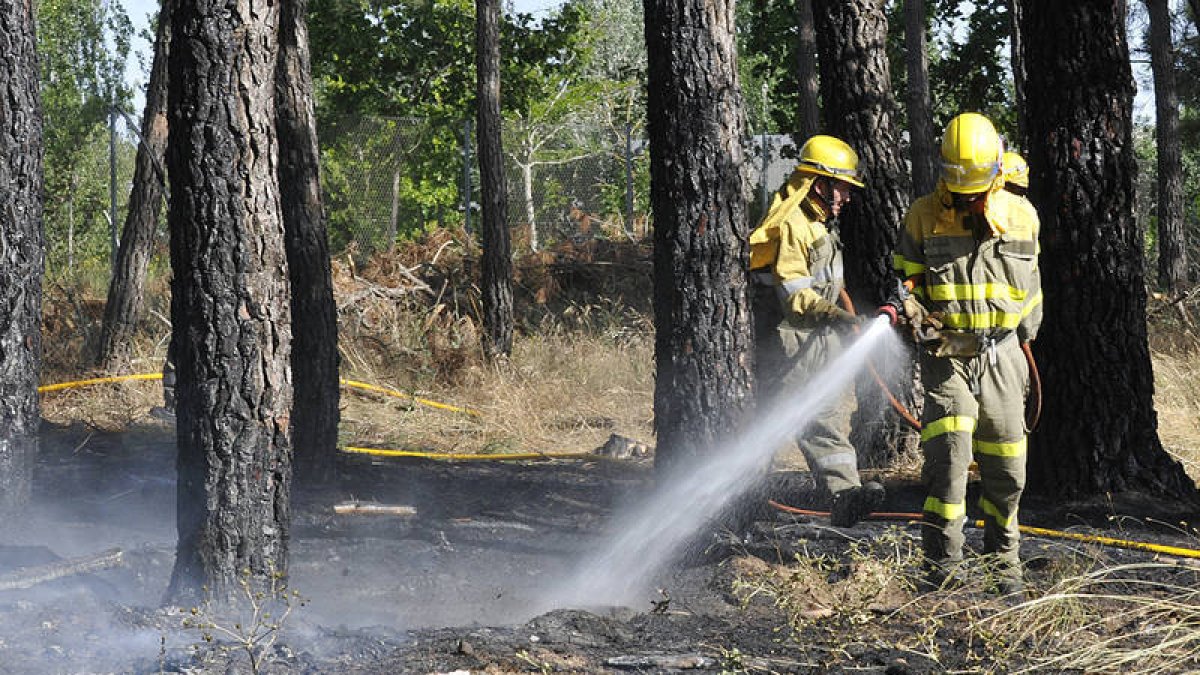 Bomberos refrescando una zona quemada. / VALENTÍN GUISANDE-