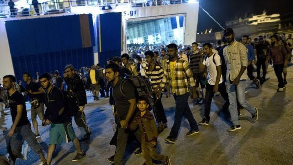 Cientos de inmigrantes desembarcan de un ferry en el puerto de El Pireo, cerca de Atenas, la noche del martes.-AFP / ANGELOS TZORTZINIS