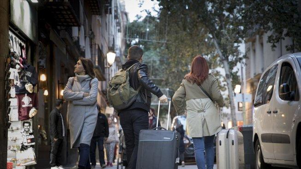 Jóvenes con maletas caminando por la calle.-