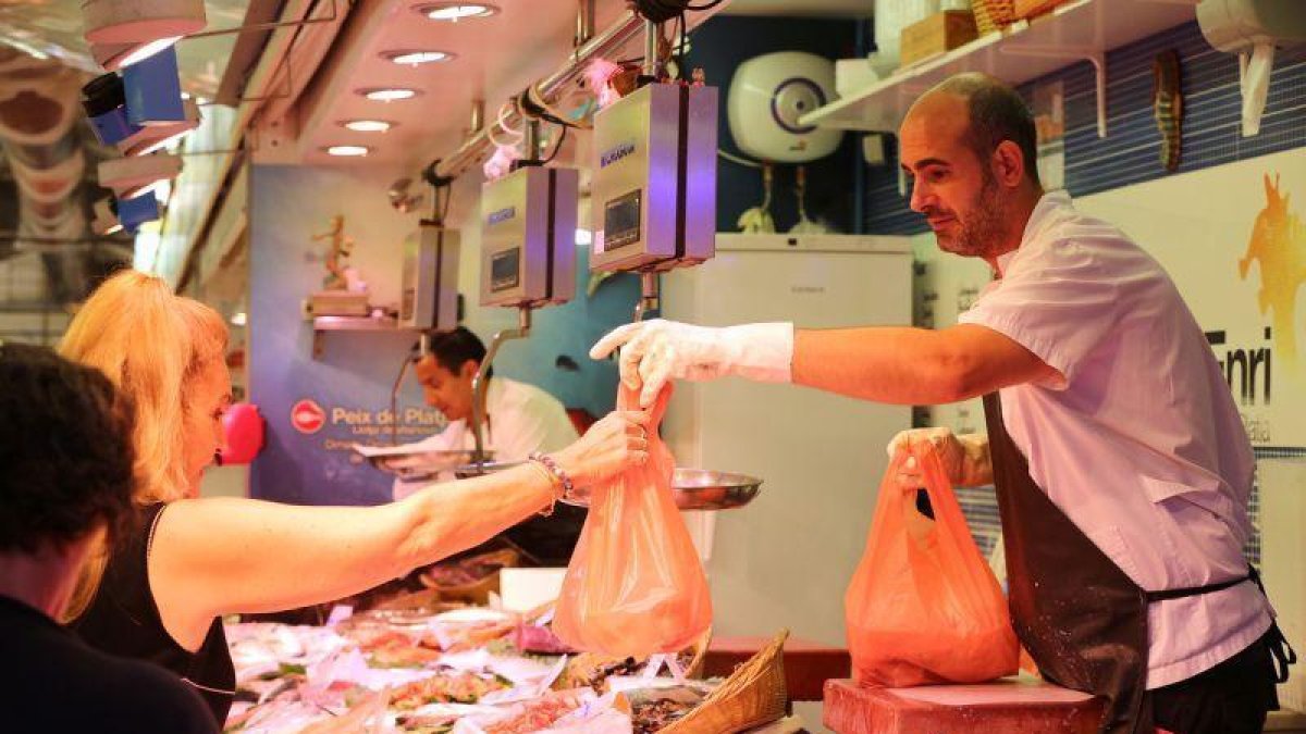 Una mujer compra pescado fresco en un mercado de Barcelona.-RICARD CUGAT