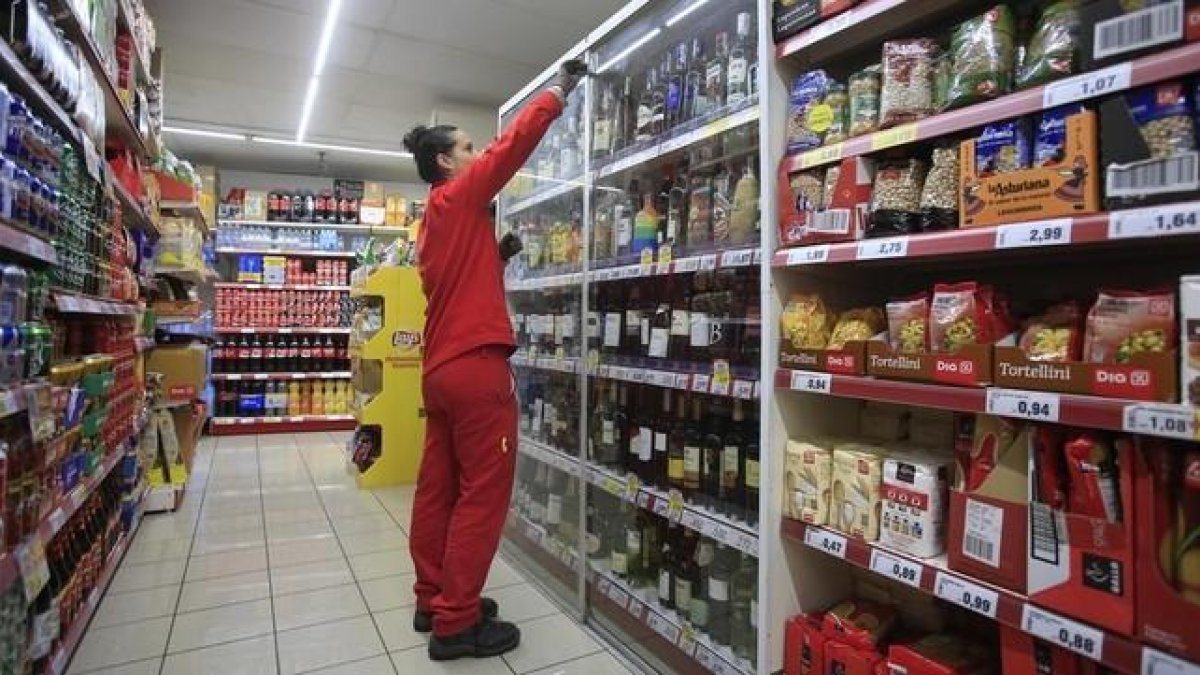 Una empleada repone los productos en un supermercado.-FERRAN NADEU