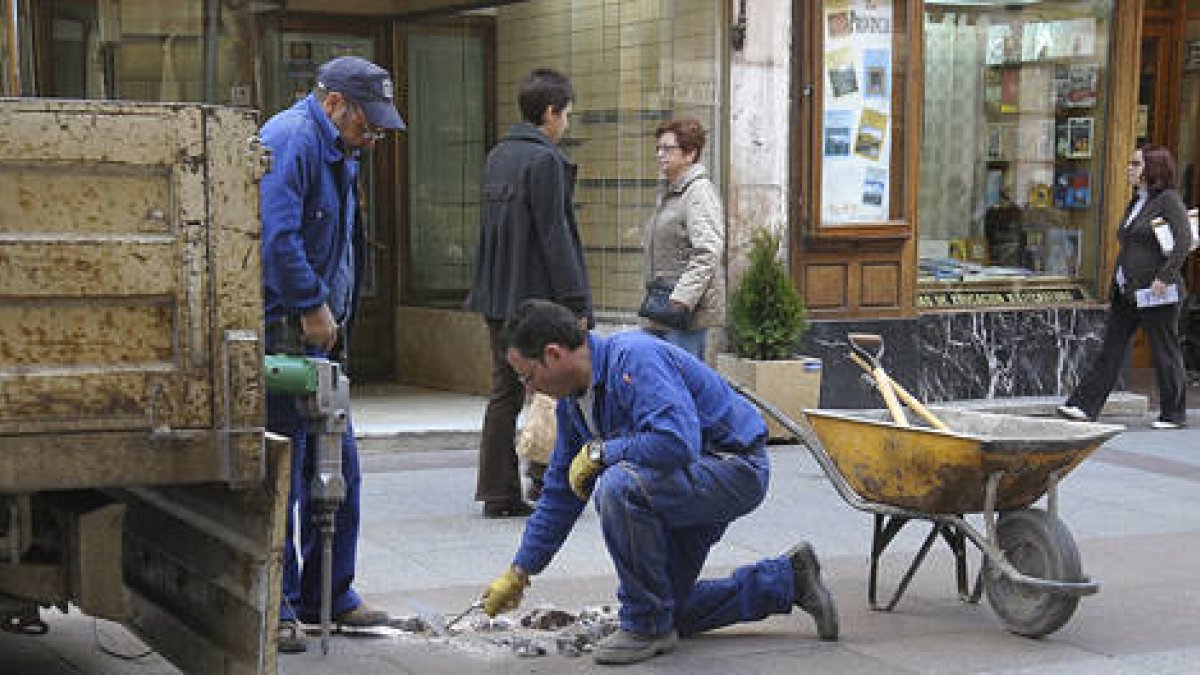 Trabajadores municipales trabajan en el Collado arreglando las baldosas que se rompen y para evitar los tropiezos de los peatones. / VALENTÍN GUISANDE-