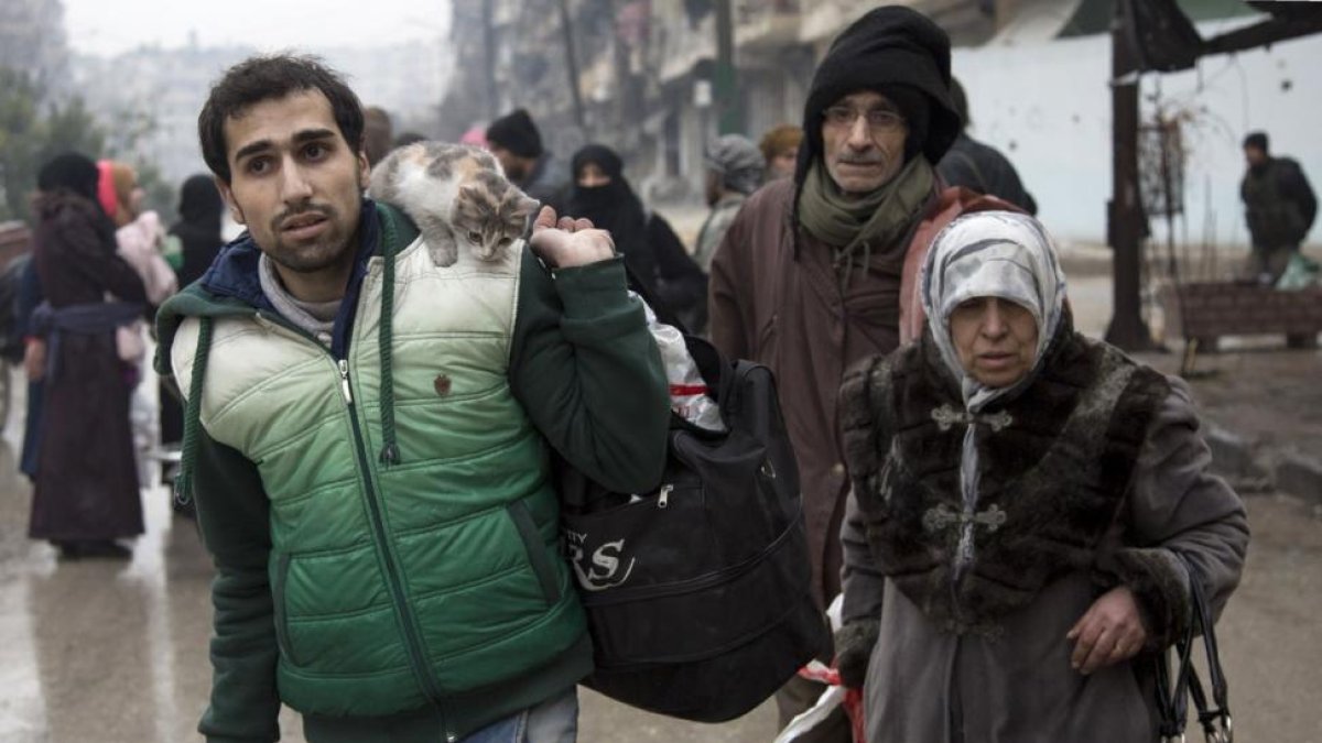 Una familia siria espera a ser evacuada de Alepo.-AFP