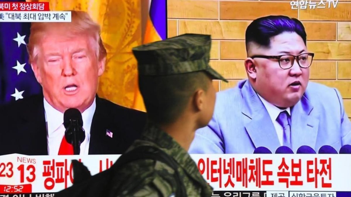 Un soldado surcoreano pasa frente a un televisor en Seúl mientras aparecen en la pantalla Donald Trump y Kim Jong un.-/ AFP / JUNG YEON-JE