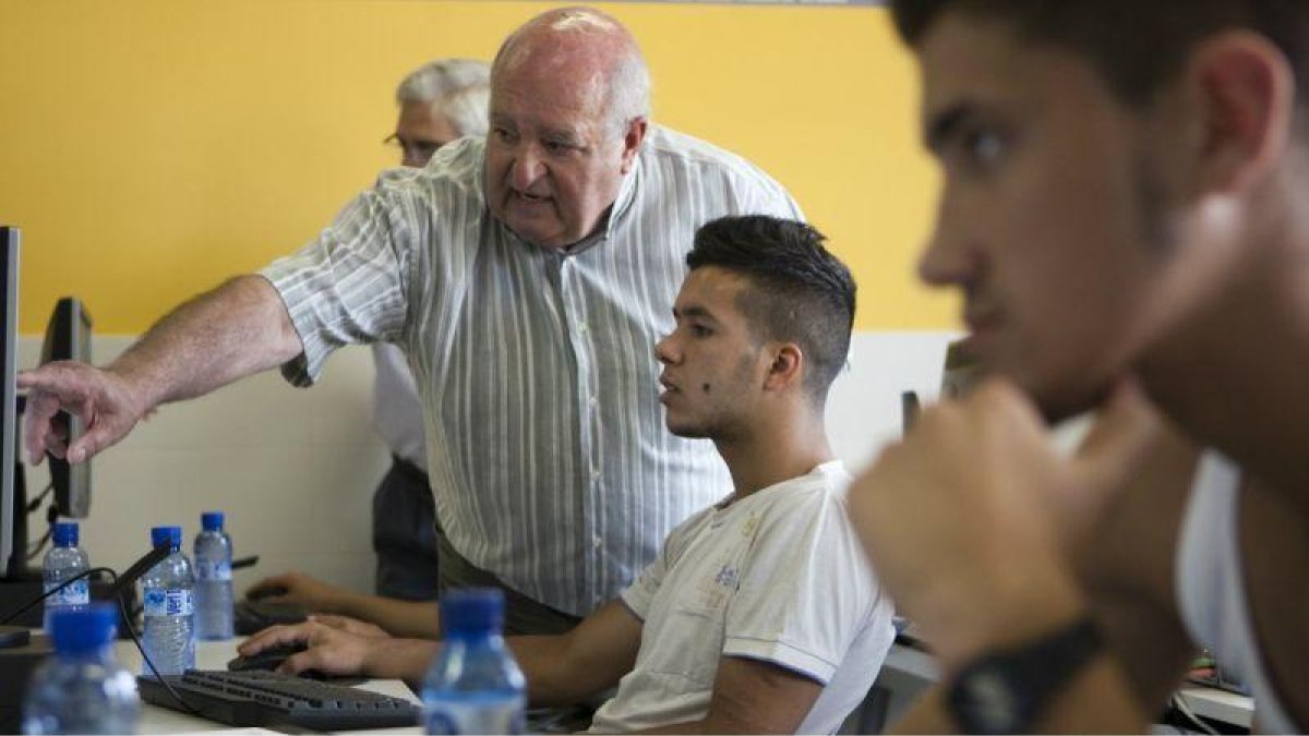 Una persona jubilada enseña de forma voluntaria informática a jóvenes, en La Roca del Vallès (Barcelona).-ALBERT BERTRAN