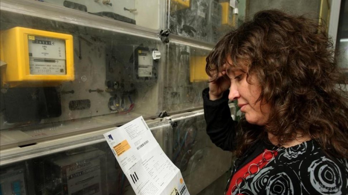Una mujer comprueba la lectura del contador de electricidad.-ALVARO MONGE