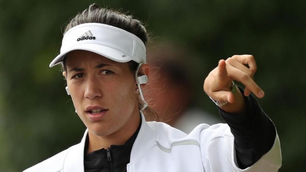 Garbiñe Muguruza se dirige al entrenamiento de este viernes, escuchando música en sus auriculares.-AFP / DANIEL LEAL-OLIVAS