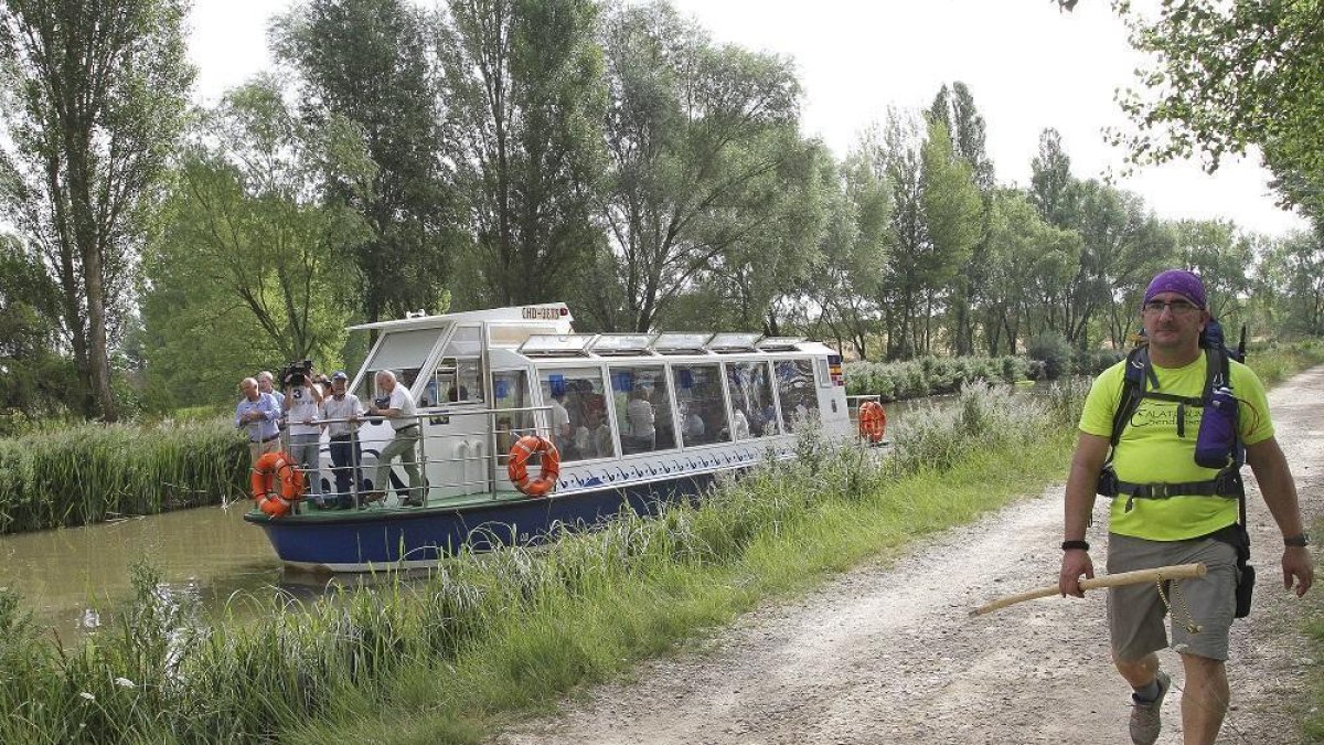 Un peregrino realiza un tramo de la Ruta Jacobea por el Camino Francés, a la orilla del Canal de Castilla, junto a la embarcación Juan de Homar.-- MANUEL BRÁGIMO