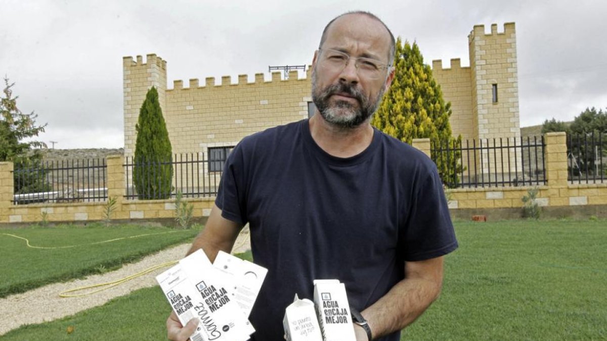 El encargado de la planta, Iván Rodríguez, posa frente al edificio en el que se encuentra el manantial con cajas de agua-LAT