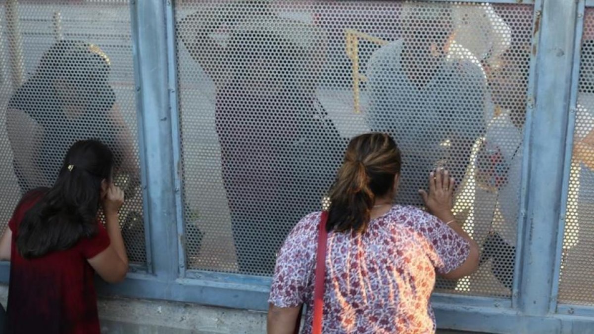 Ana Pineda (a la derecha) habla con sus familiares desde el lado estadounidense de la frontera de Nogales.-RICARDO MIR DE FRANCIA
