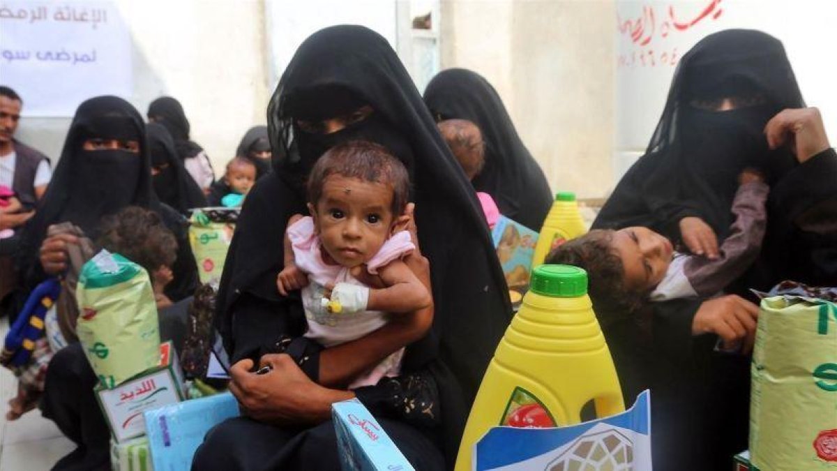 Mujeres yemenís sostienen a sus hijos mientras esperan el reparto de comida en la ciudad de Al Hudayda, en la costa oeste del país.-ABDO HYDER (AFP)