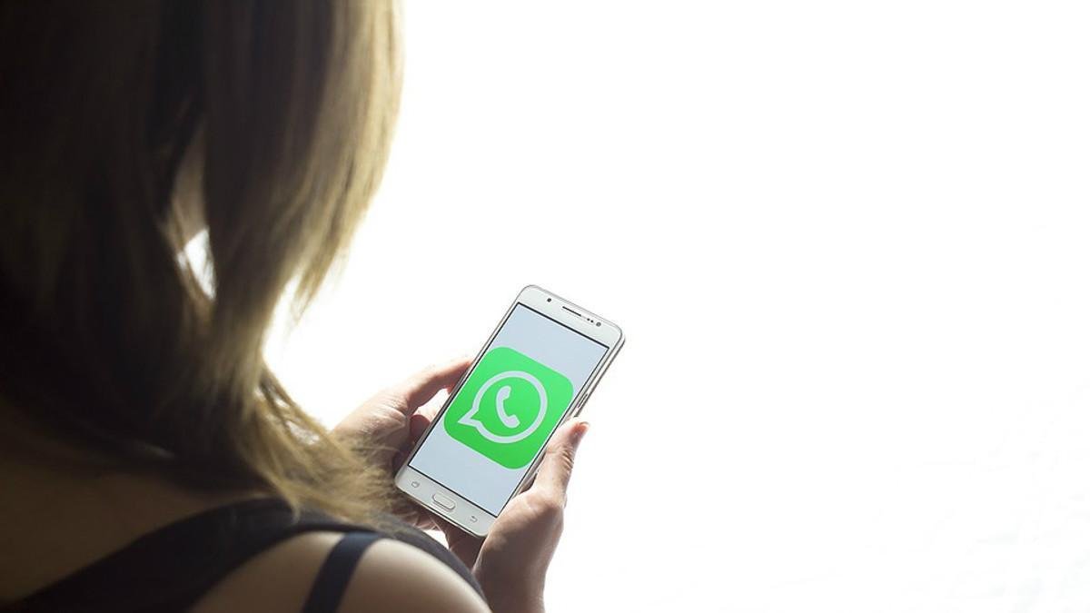 Una chica mira la pantalla de su teléfono móvil, con el logo de Whatsapp.-EL PERIÓDICO