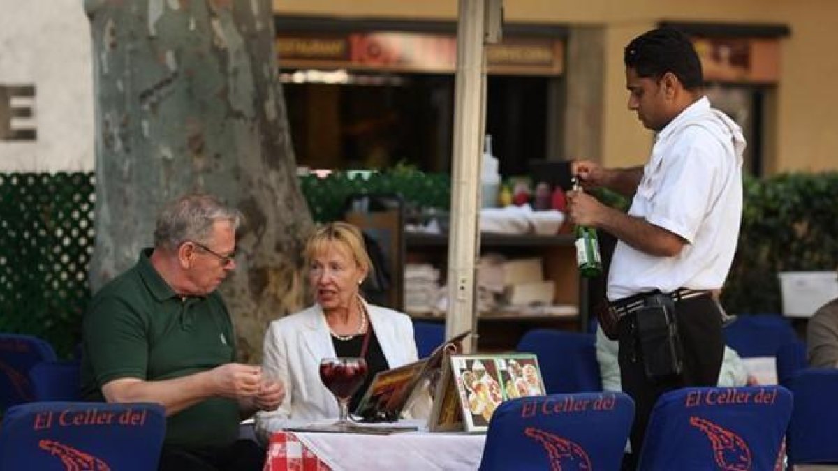 Un camarero atiende a unos clientes en establecimiento de Barcelona.-
