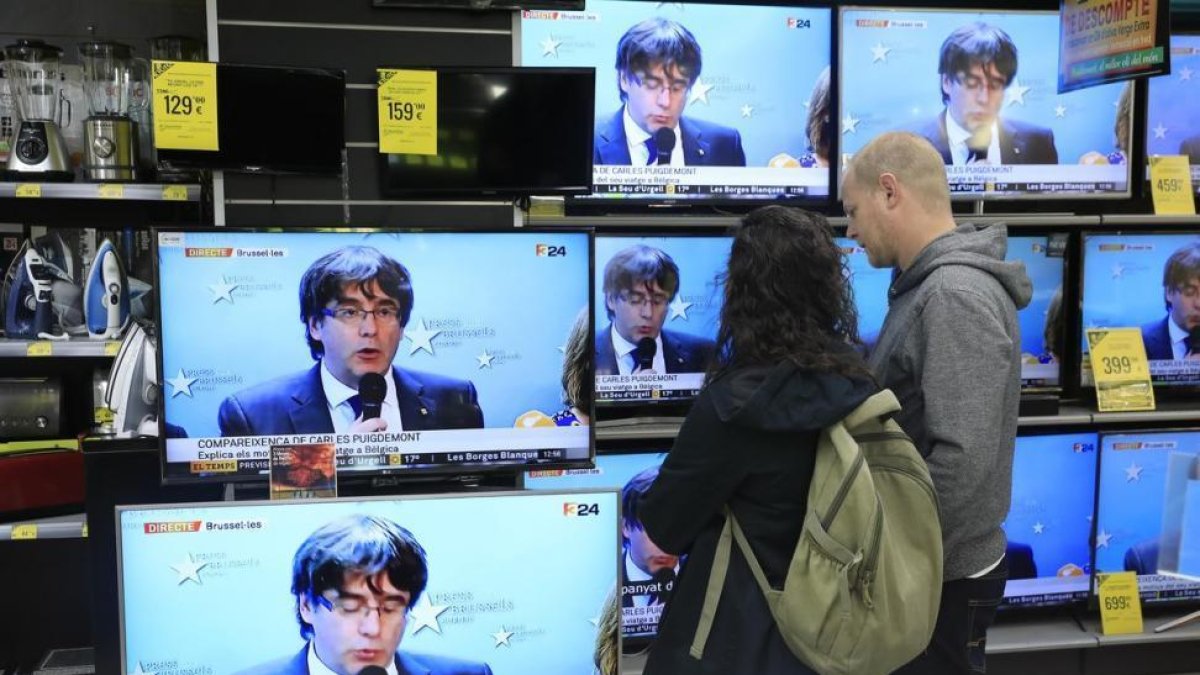 Seguimiento en una tienda de Bacelona de la rueda de prensa de Puigdemont en Bruselas el pasado 31 de octubre.-/ FERRAN NADEU