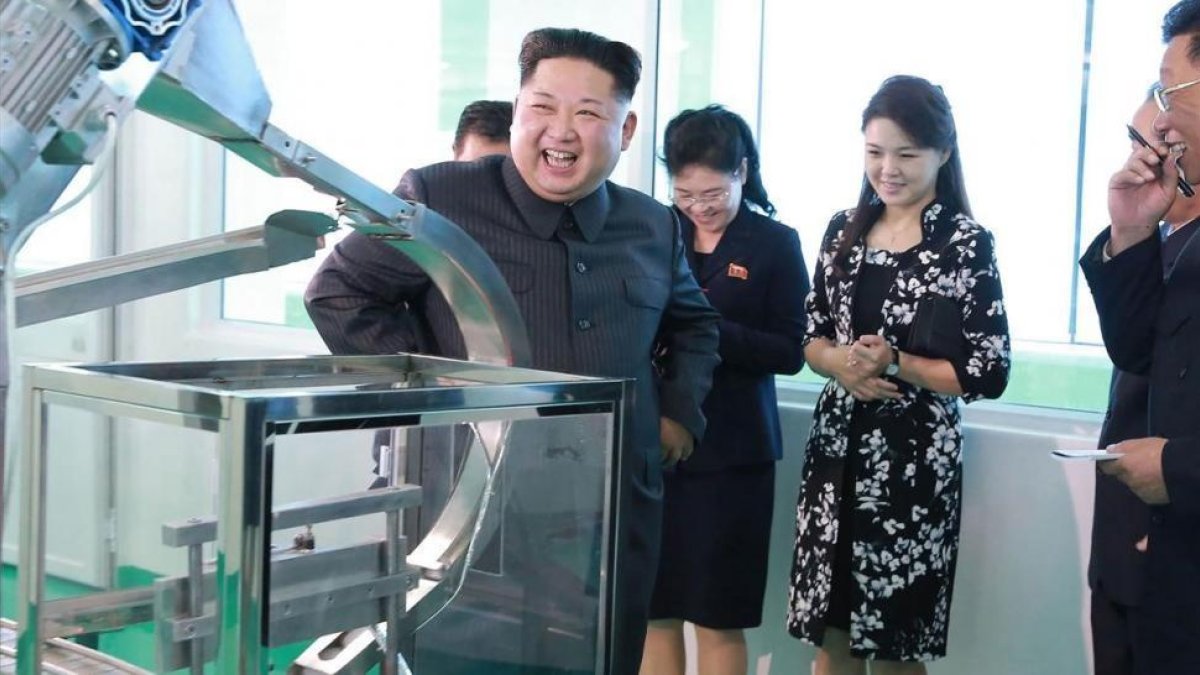 Kim Jong-un durante la visita a la fábrica, junto a su mujer, Ri Sol-ju (segunda por la derecha), en una foto difundida el domingo por la KCNA.-AFP