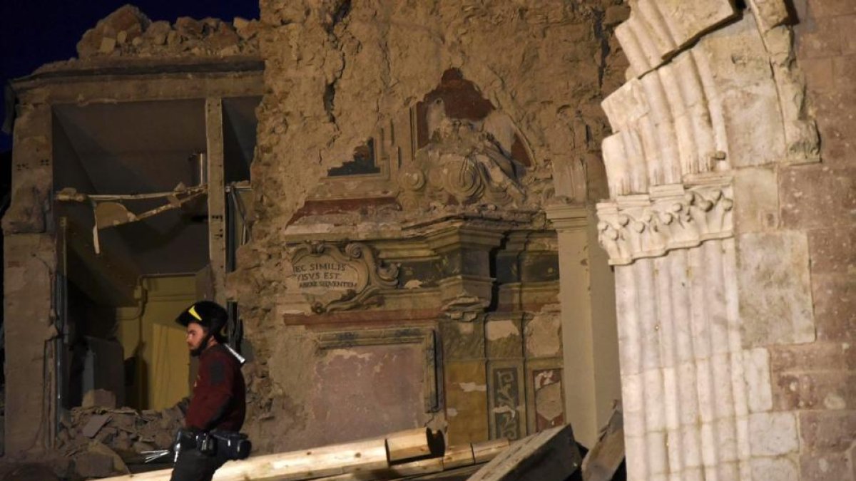 Un bombero trata de recuperar objetos de la basílica de San Benedetto, en Norcia, dañada por los terremotos.-EFE / PIETRO CROCCHIONI