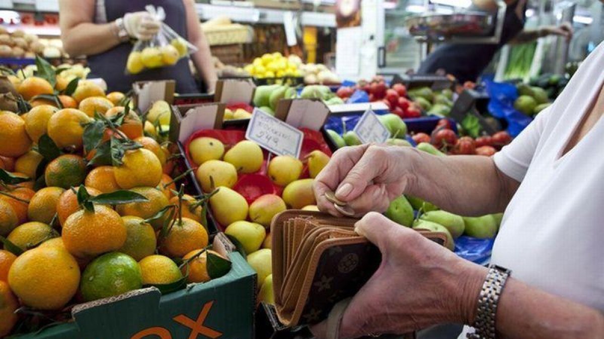 Una mujer llena la cesta de la compra en un mercado de Barcelona.-FERRAN NADEU