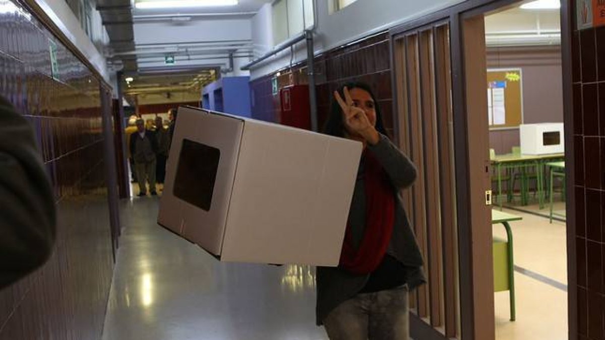 Una voluntaria hace el signo de la victoria antes de abrir el punto de participación, en Girona.-