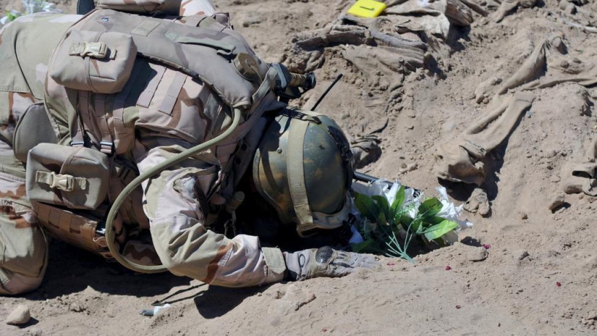 Un soldado iraquí reza ante la tumba de uno de los militares masacrados por el Estado Islámico en el 2014.-REUTERS