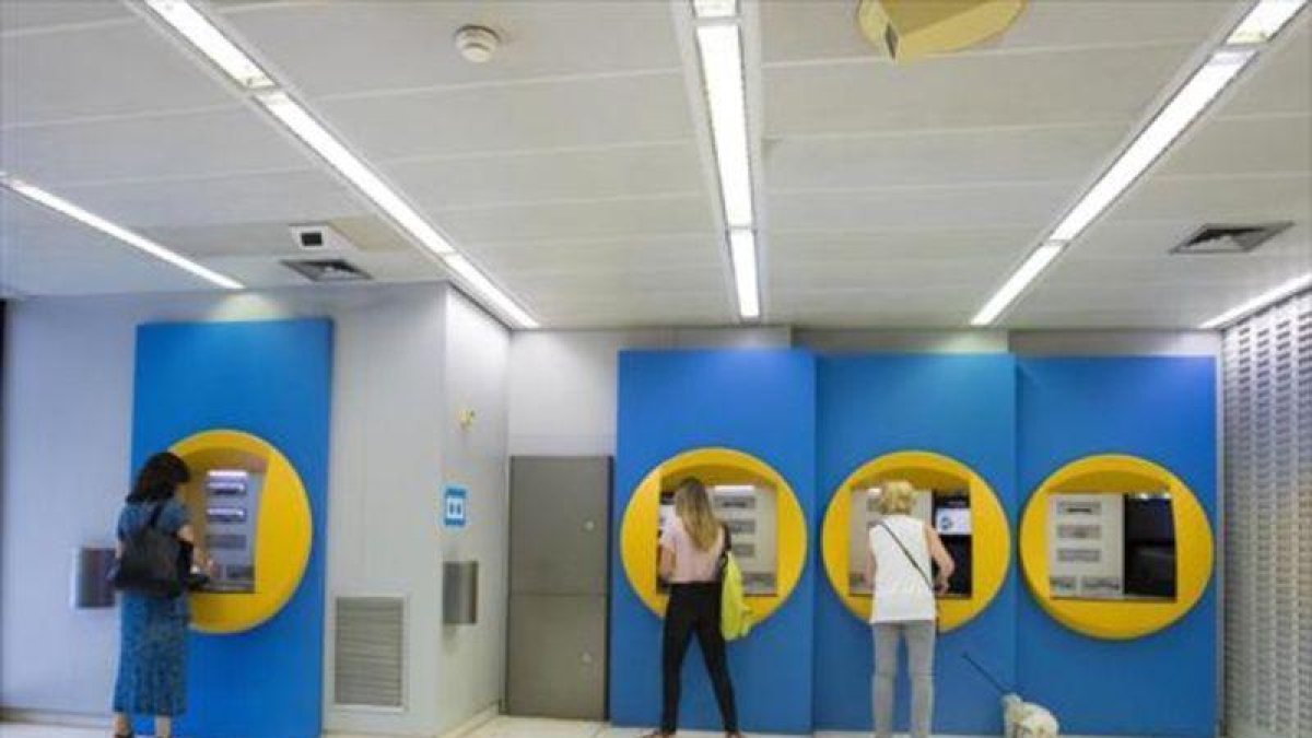 Clientes en cajeros de CaixaBank.-FERRAN NADEU