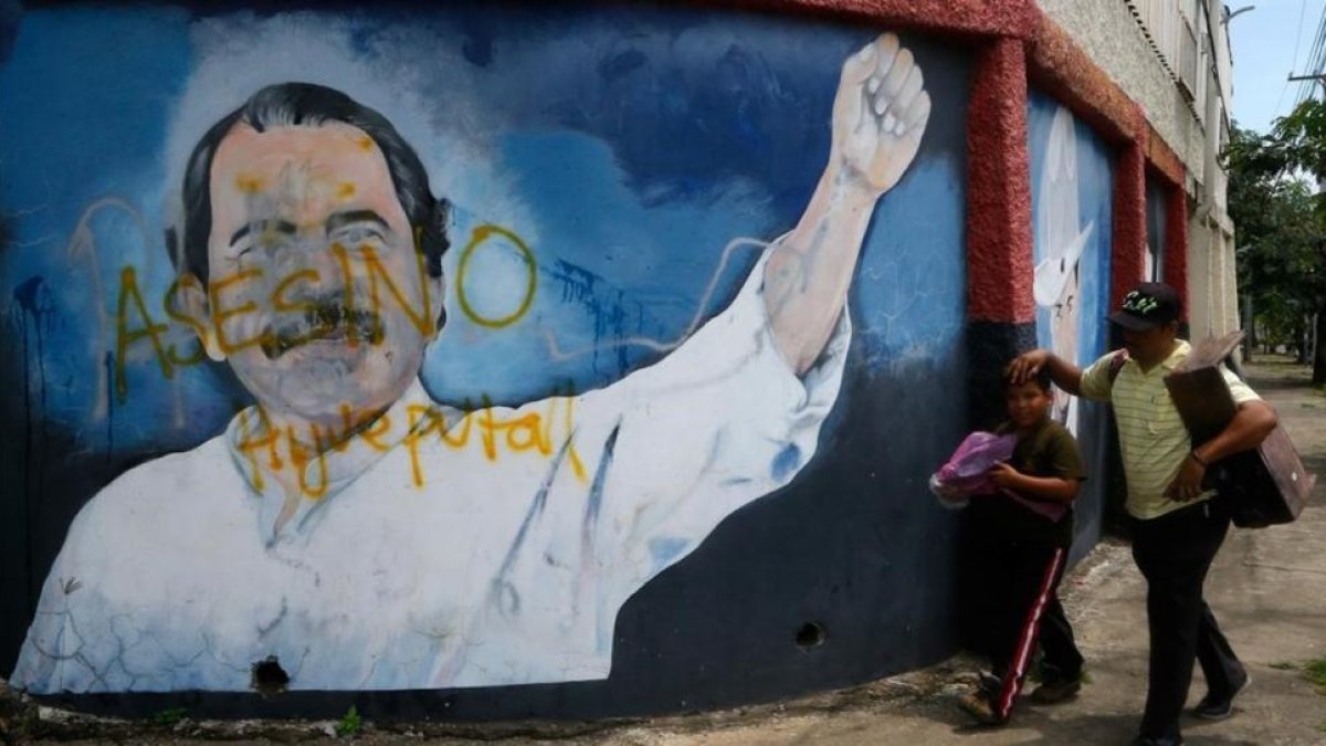 Dos personas pasan junto a un mural de Daniel Ortega en Managua-OSWALDO RIVAS