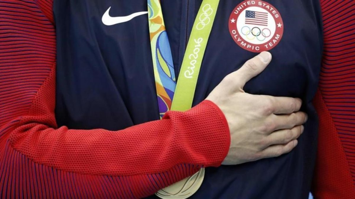 Michael Phelps se lleva la mano al pecho mientras suena el himno de EEUU, tras el triunfo en el relevo 4x100. La última de sus 28 medallas olímpicas.-AFP / ODD ANDERSEN