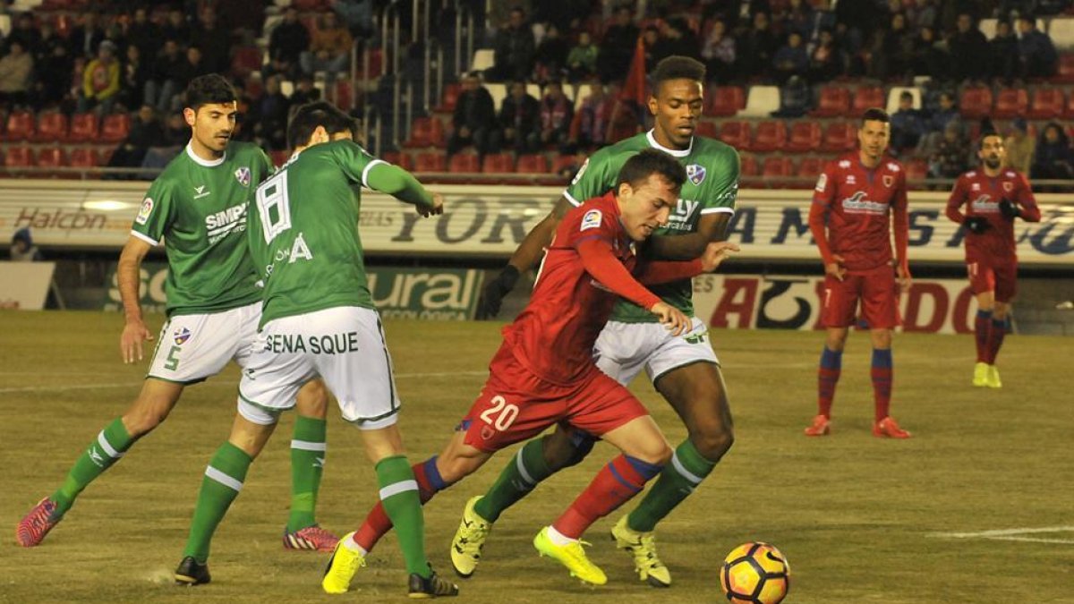 Pablo Valcarce conduce un balón ante varios jugadores del Huesca.-MARÍA FERRER