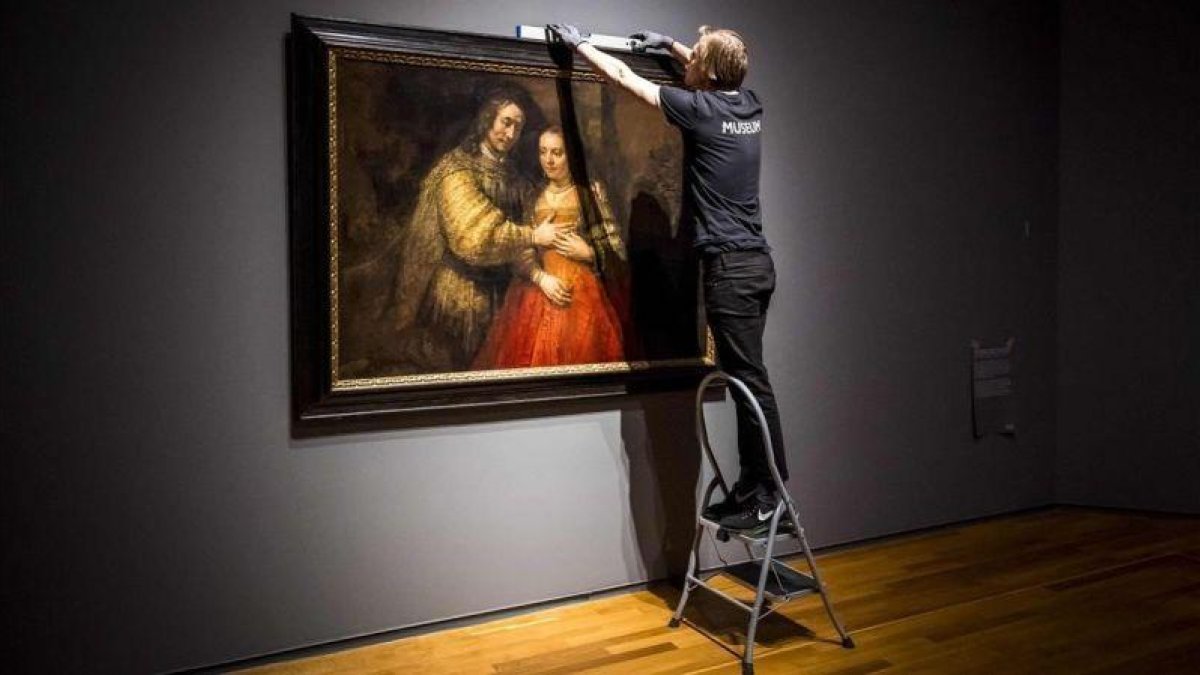 Unos operarios del Rijksmuseum cuelgan La novia judía, de Rembrandt, para la exposición que el museo dedica al artista en el 350 aniversario de su muerte.-AFP / LEX VAN LIESHOUT