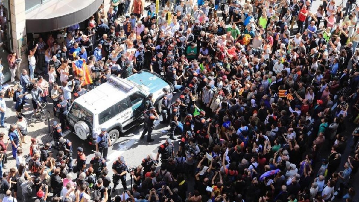 Decenas de personas intentan impedir que salga el coche de la Guardia Civil tras el registro al Departament dAfers Exteriors de la Generalitat.-FERRAN NADEU